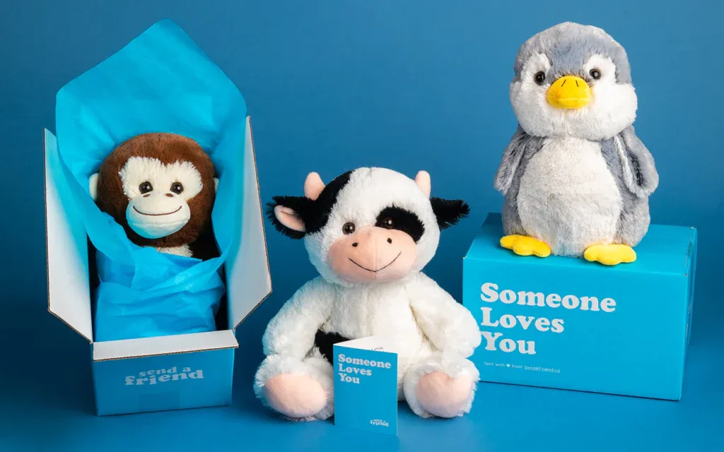 Plush monkey, cow, and penguin toys with blue gift boxes and cards.