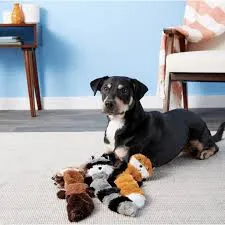 Black dog lying on floor with three stuffed animal toys nearby.