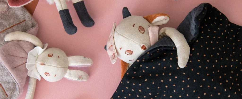 Close-up of soft plush toys resting on a pink surface.