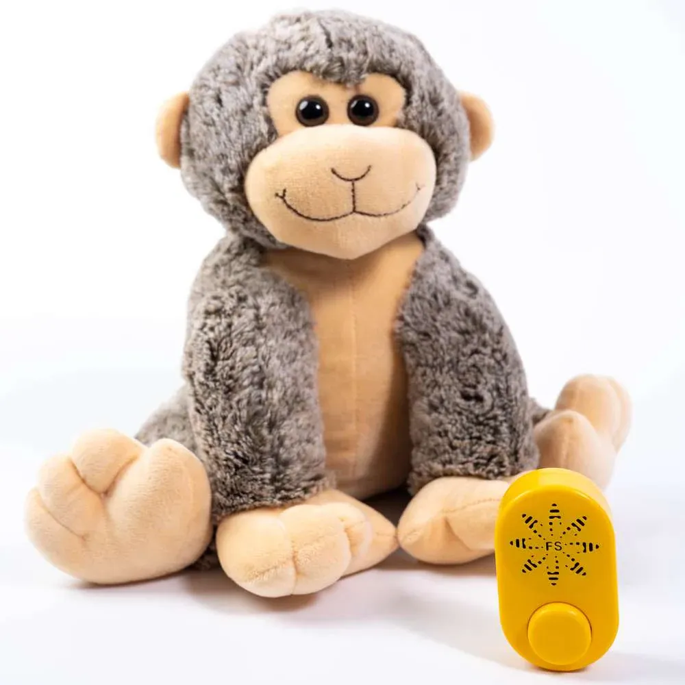 Smiling plush monkey sitting next to yellow sound module with button.