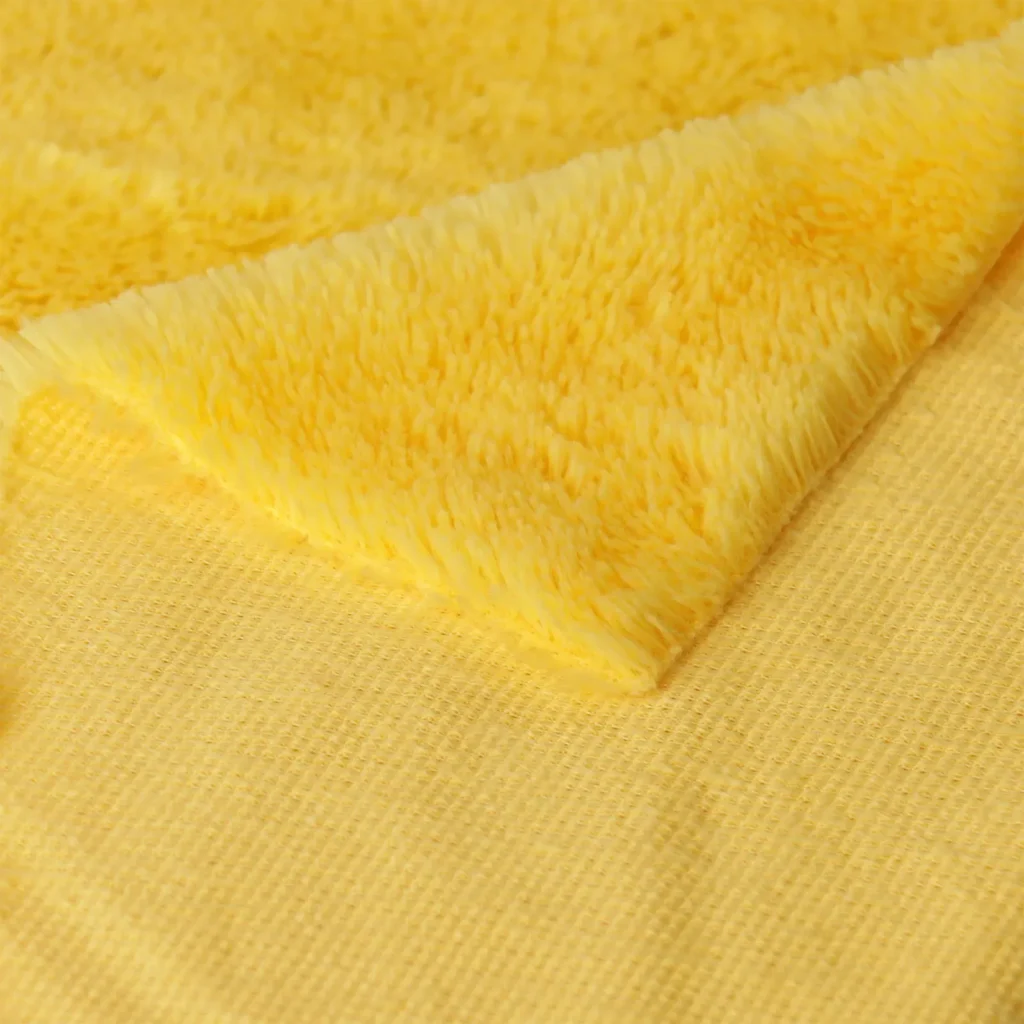Close-up of soft yellow plush fabric showing texture and backing.