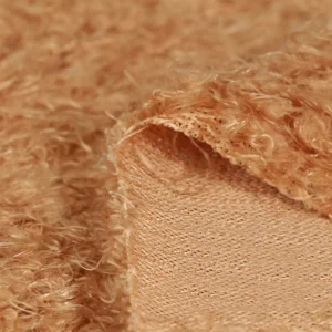 Close-up texture of brown curly plush fabric with knitted backing.