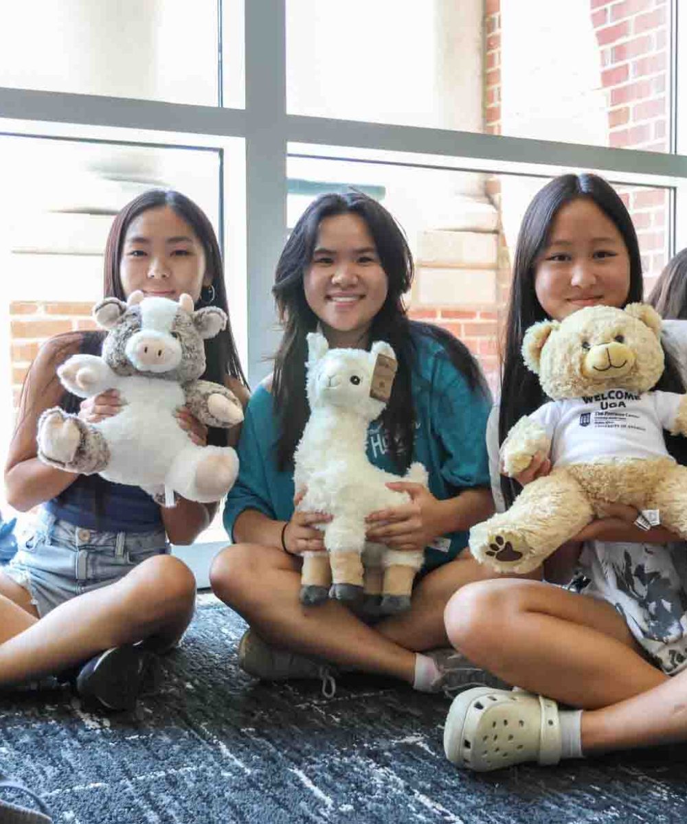 Three girls holding stuffed animals indoors