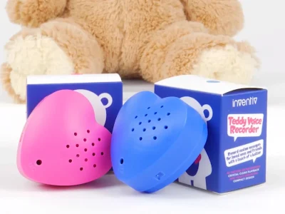 Pink and blue heart-shaped voice recorders with packaging in front of teddy bear.